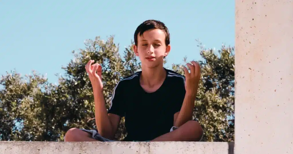 Supporting Teen Self-Care and Emotional Well-being After Trauma 3 Teenager practicing mindfulness meditation outdoors for self-care and emotional healing post-trauma. Supporting Teen Self-Care